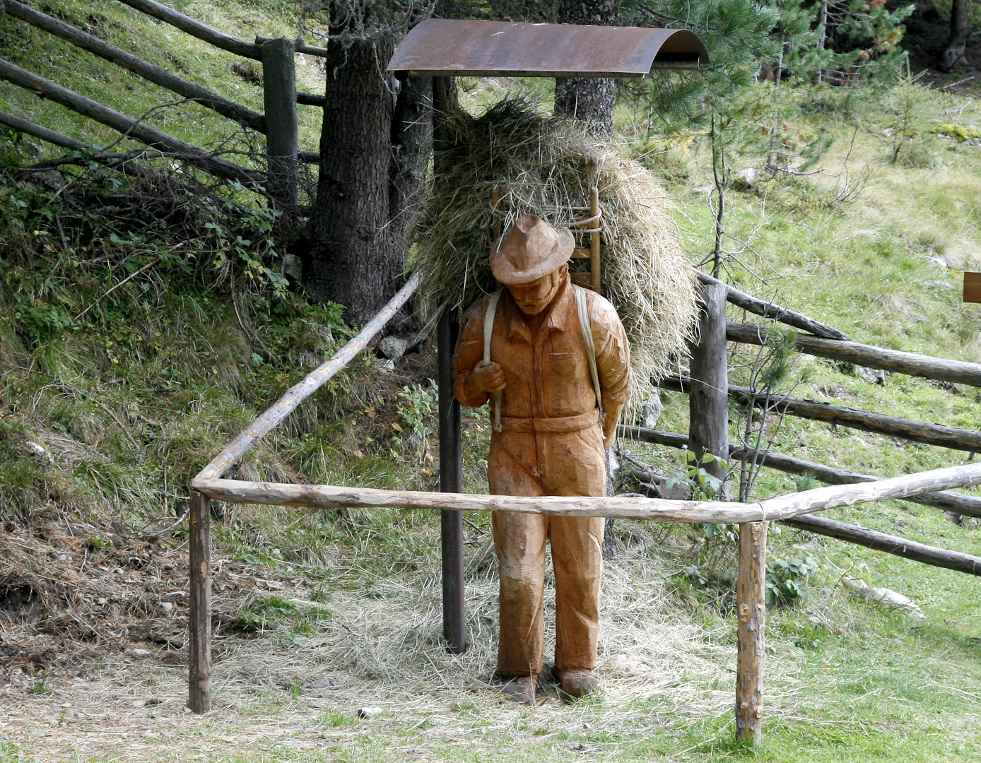 Holzskulptur eines Bauern mit Heubündel am Lehrpfad im Mühlbacher Talile